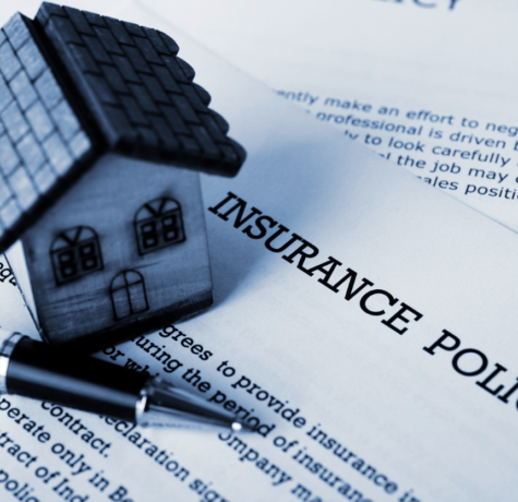 toy house and pen set on insurance policy document
